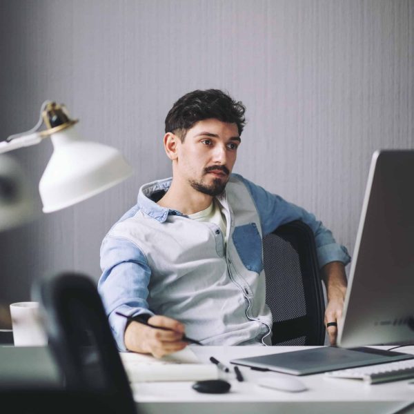 Businessman working at desk with computer and lamp, reflecting professionalism and expertise in garage door services.